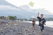 Kids flying their kites on the black sands of Amed, Bali
