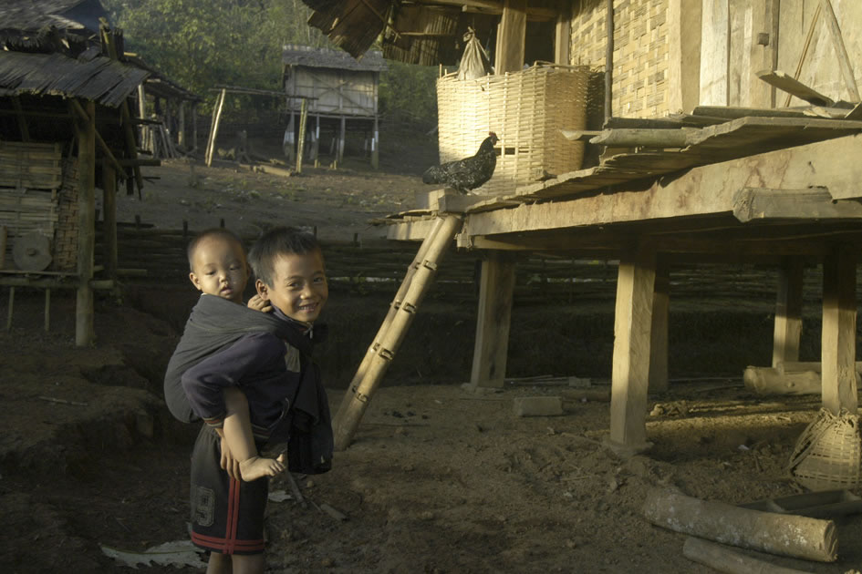 Young boy babysitting his even younger brother, Ahka village