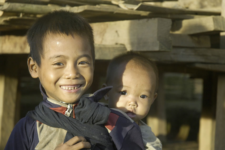 Young boy babysitting his even younger brother, Ahka village